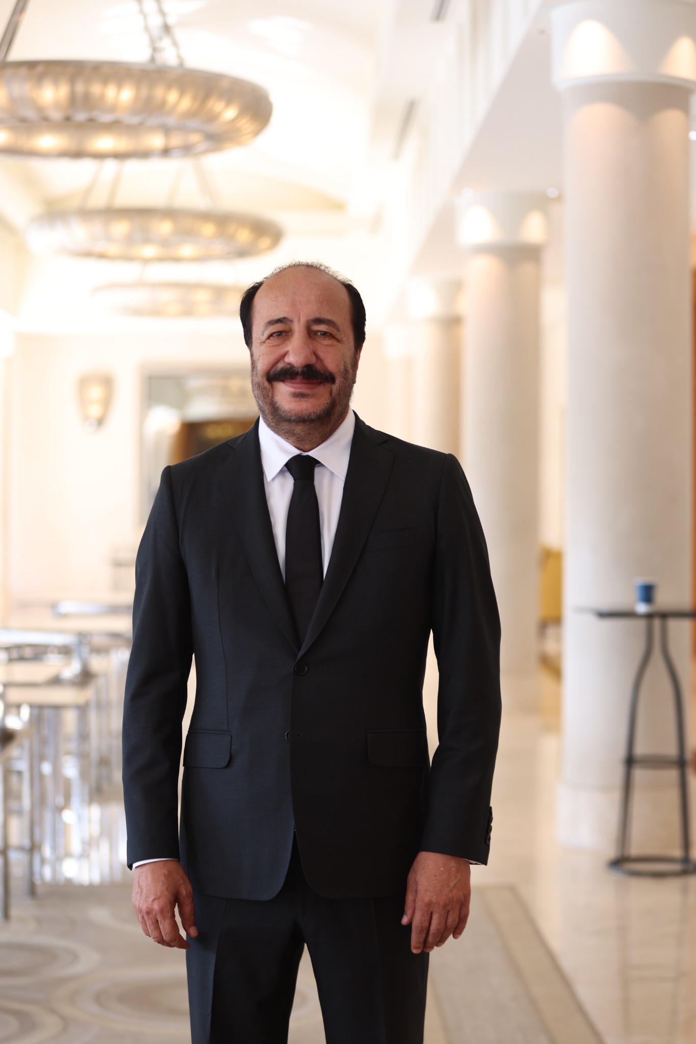 Adnan Dalgakıran ayakta, takım elbiseli portre